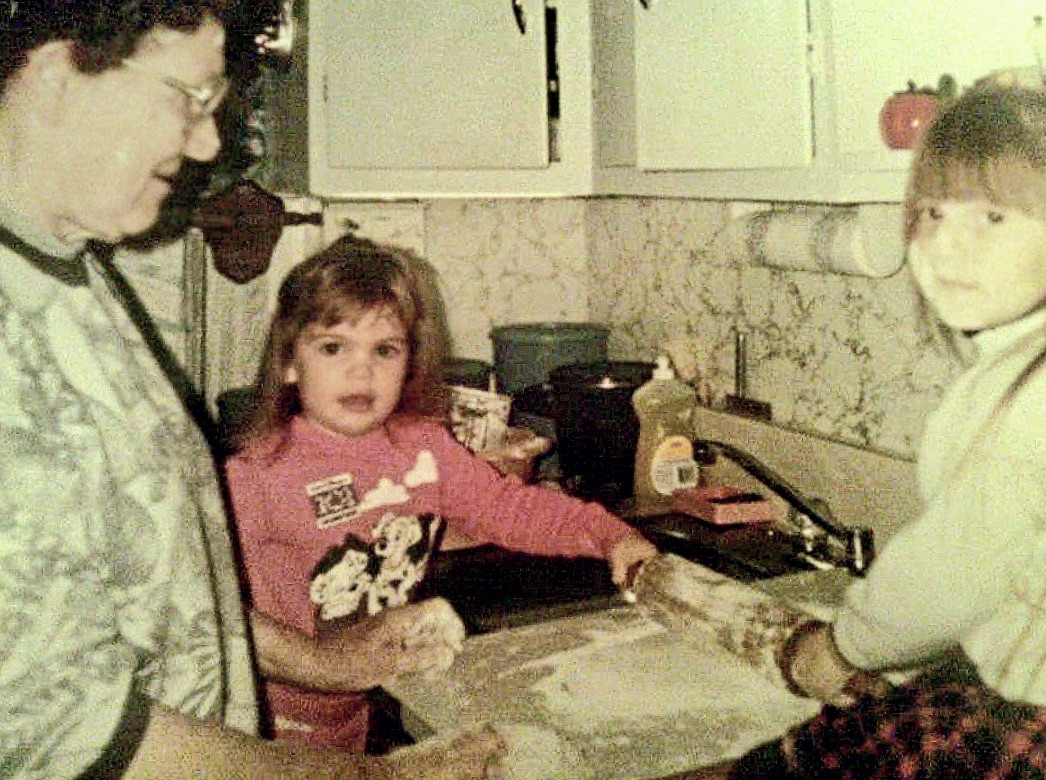 Article author and sister making dumplings with their great grandmother in an old family photo