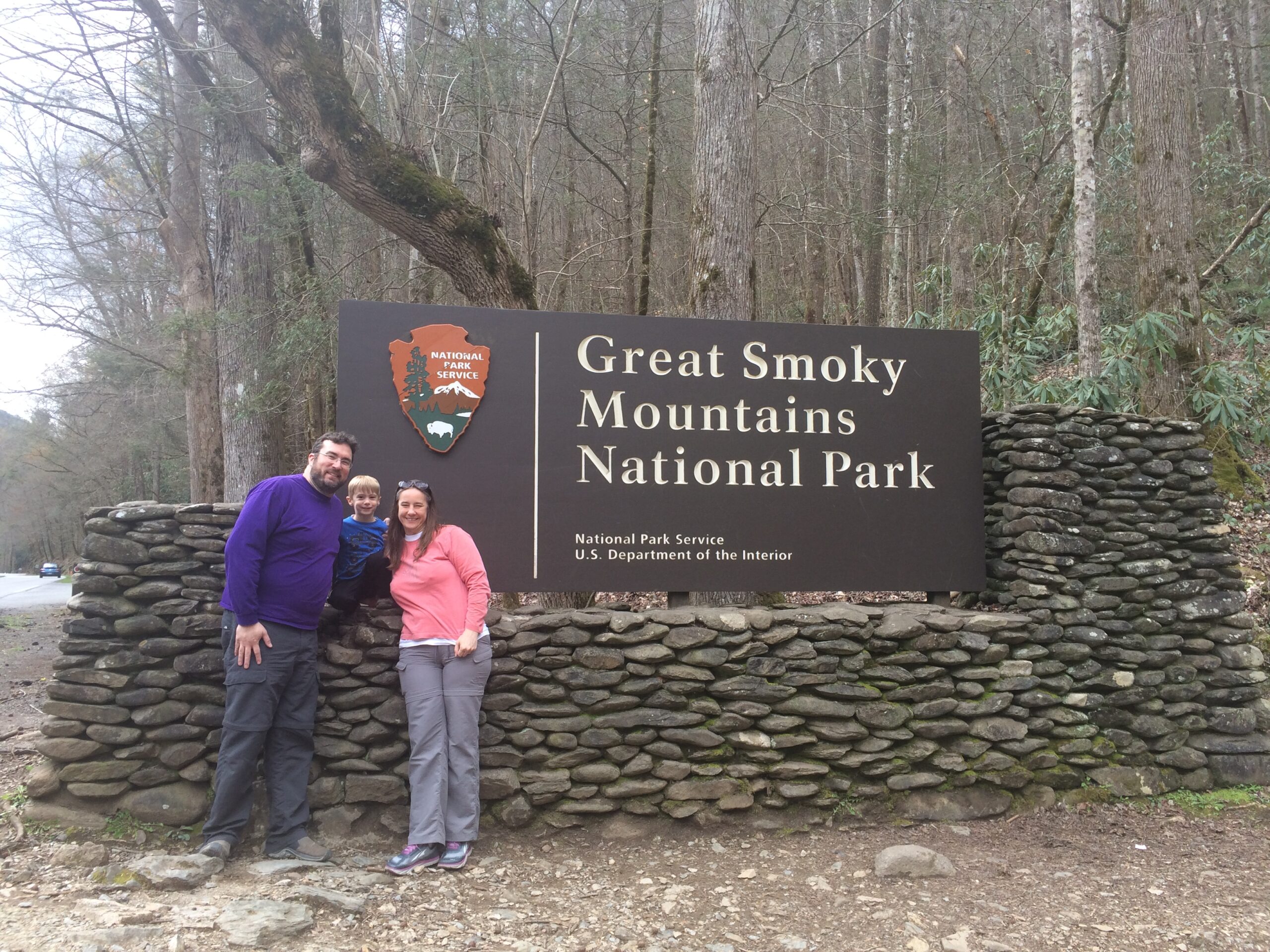 Man, Woman, and Child standing outside the Great Smoky Mountains National Park sign